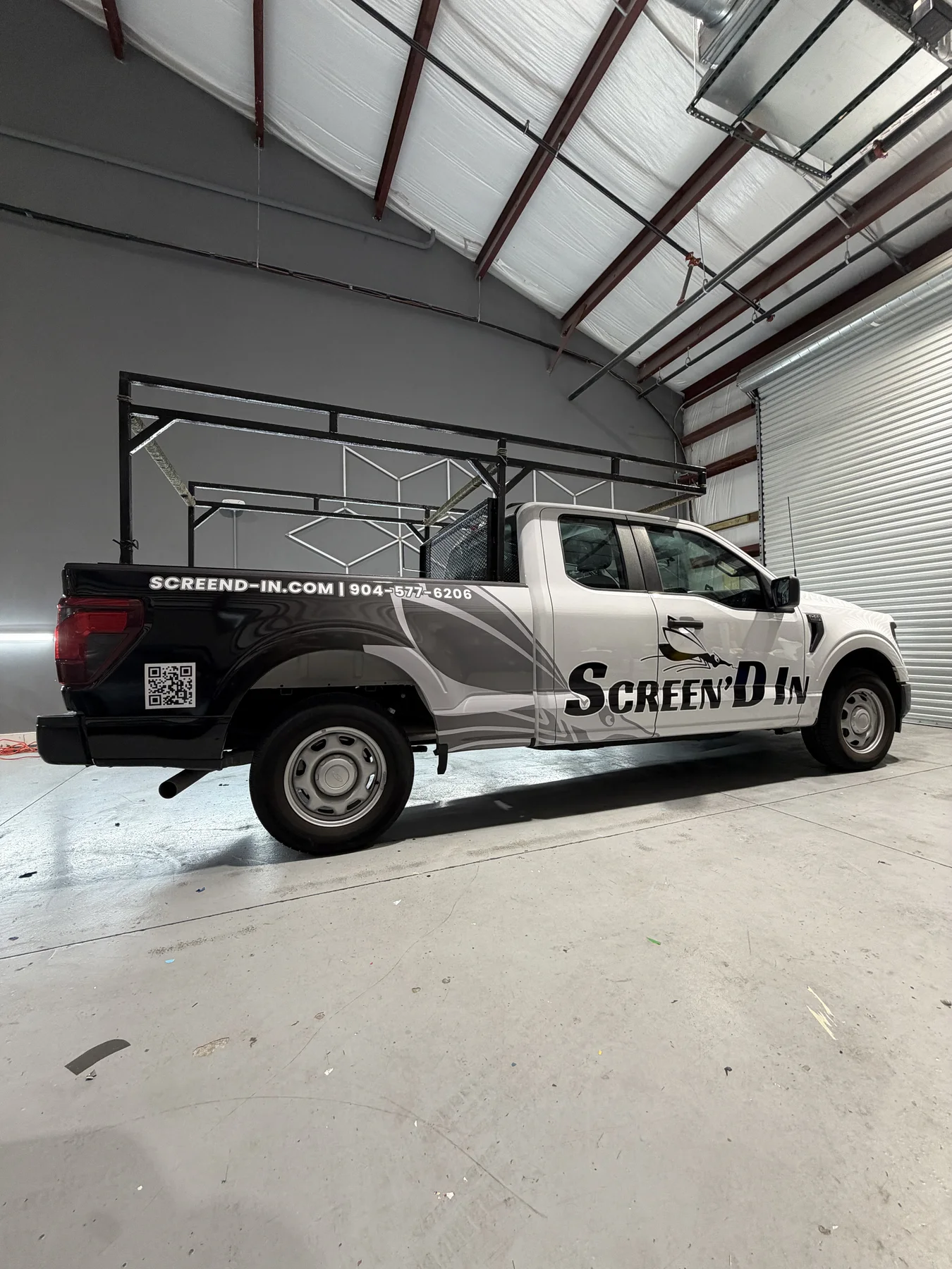 Screen'd-In black, white, and gray wrapped commercial rack-body pickup